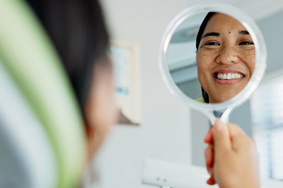 Woman smiling while looking at reflection in mirror