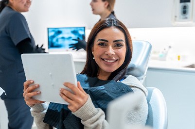 Woman smiling while holding mirror in treatment room