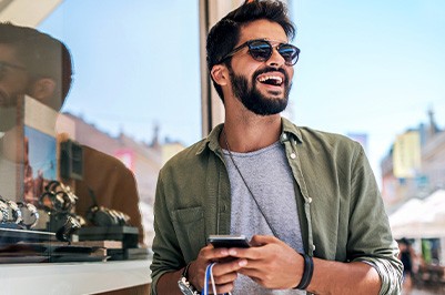 Man with sunglasses smiling while shopping outside