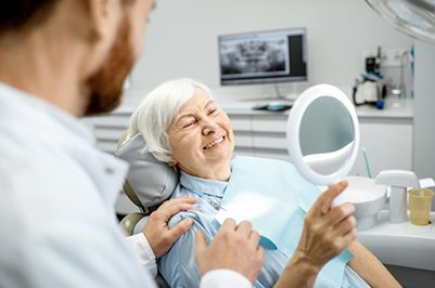 a patient checking her smile with a mirror