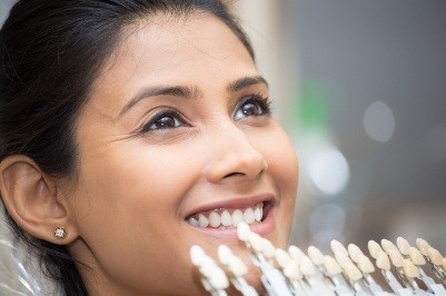 Woman's smile compared with dental bonding color chart