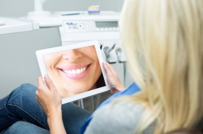 Woman looking at smile makeover design on tablet computer