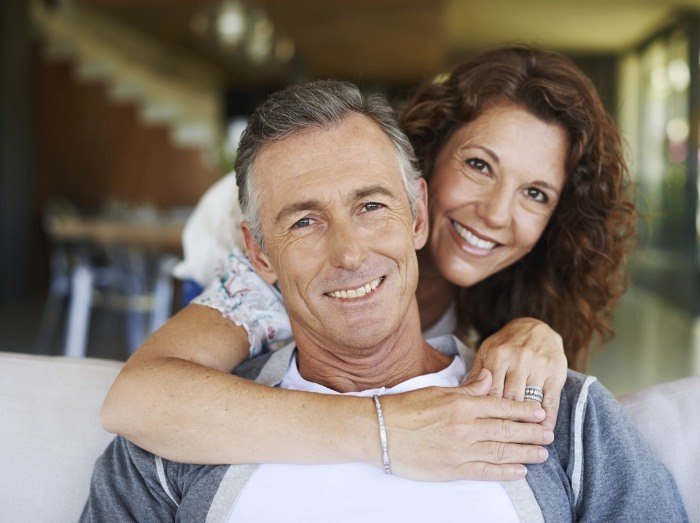 Man and woman with healthy smiles after dental crown supported fixed bridge