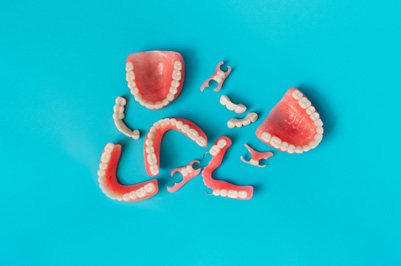 Bird’s eye view of several sets of dentures with light blue background