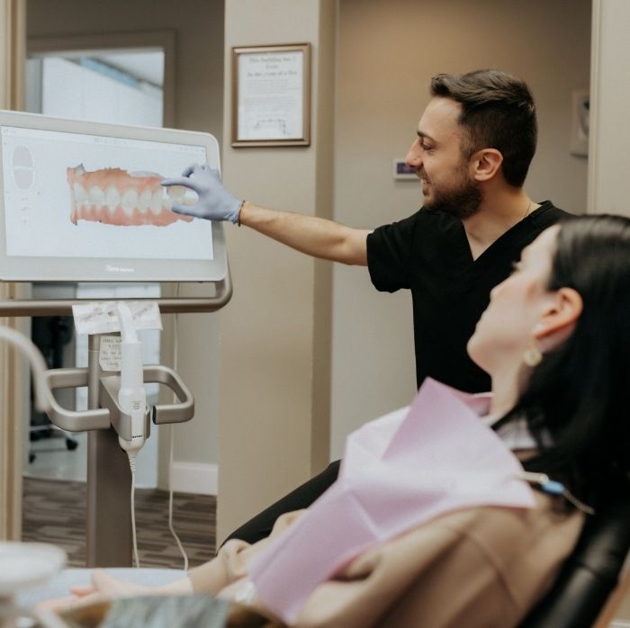 Doctor Yazan Abou Zakhem showing a patient digital models of their teeth on a screen