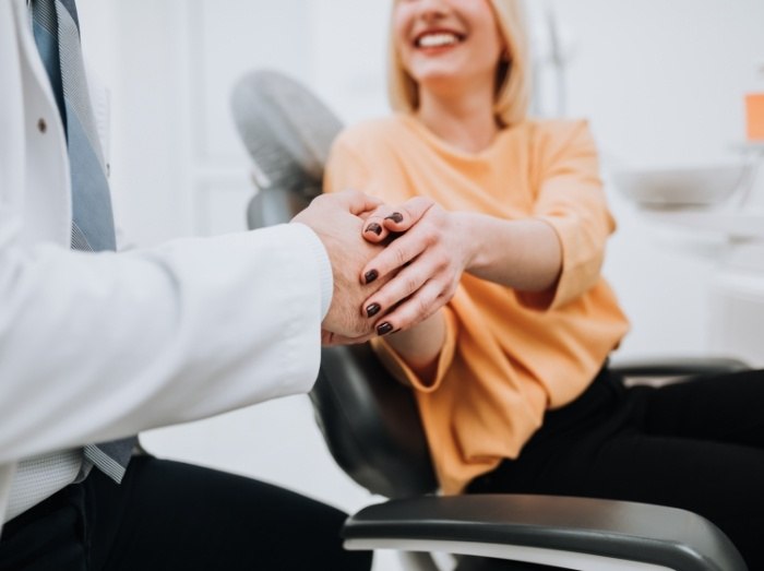 Woman shaking hands with dentist during emergency dentistry visit