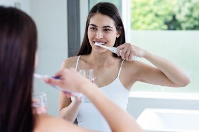 Woman brushing teeth to prevent dental emergencies