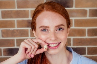 Woman holding up an extracted tooth