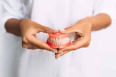 Dentist carefully holding a full denture