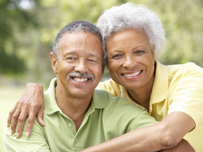 Man and woman with full smiles after dental implants