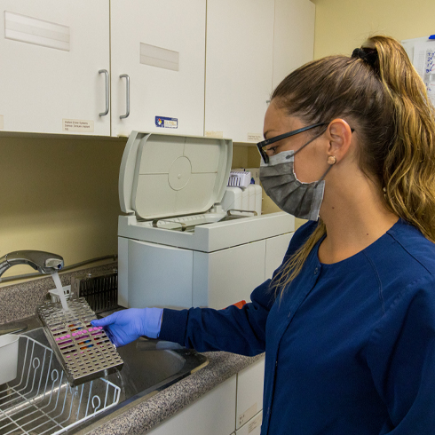 Dental team member sanitizing dental tool