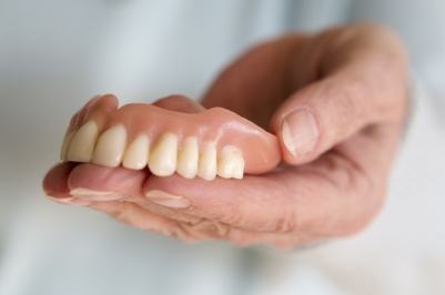 Hand holding denture