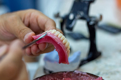 closeup of technician crafting prosthetic teeth 