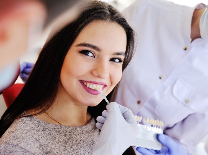 Woman's smile compared with porcelain veneers color option