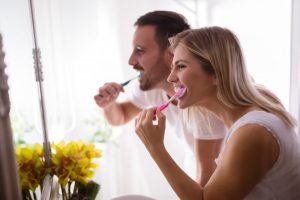 Man and woman brushing their teeth.