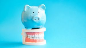 Piggy bank atop model teeth represent how to save money