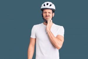 man with bike helmet having a knocked-out tooth and facial pain