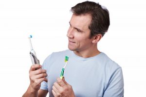 A man examining two toothbrushes.