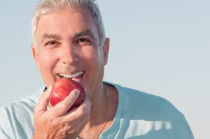 Man eating an apple with dentures