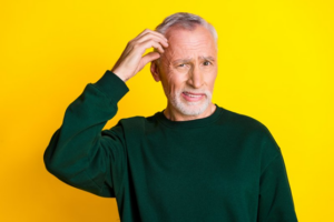 Man scratching his head on criminally bright yellow background
